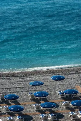a group of chairs and umbrellas on a beach at Hôtel West End Promenade in Nice