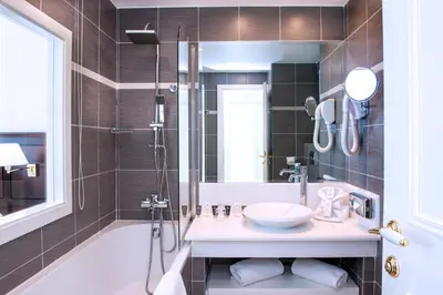 a bathroom with a sink and a shower and a tub at Hôtel West End Promenade in Nice