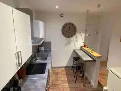 a kitchen with a counter and a clock on the wall at Nice Grand appartement face jardin in Nice