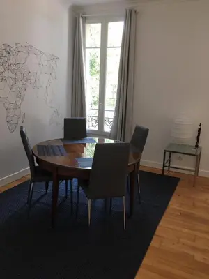 a dining room table with chairs and a laptop on it at Nice Grand appartement face jardin in Nice