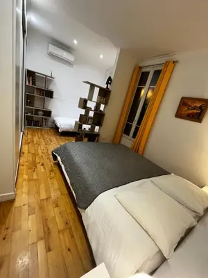 a bedroom with a bed and a wooden floor at Nice Grand appartement face jardin in Nice
