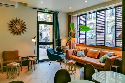 a living room with a couch and a table at Hôtel de France, un hôtel AMMI in Nice
