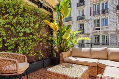 a patio with a couch and chairs on a balcony at Hôtel de France, un hôtel AMMI in Nice