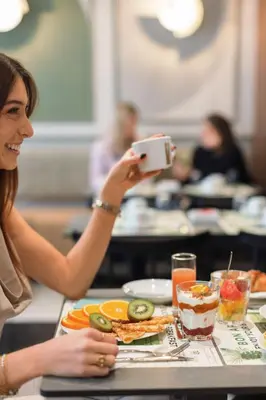 a person holding a drink in front of a tray of food at Hotel Khla Nice in Nice