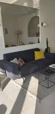 a living room with a blue couch and a mirror at Vue mer exceptionnelle entre Nice et Monaco in Villefranche-sur-Mer
