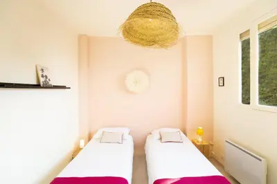 two beds in a small room with a chandelier at Vue mer exceptionnelle entre Nice et Monaco in Villefranche-sur-Mer