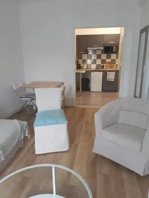 a living room with a white chair and a table at T2 entièrement équipé, proche toutes commodités in Nice