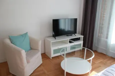 a living room with a tv and a chair at T2 entièrement équipé, proche toutes commodités in Nice
