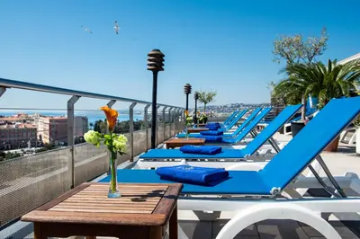 a row of blue lounge chairs and tables on a roof at Hotel Aston La Scala in Nice