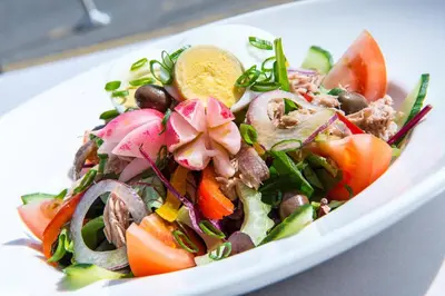 a salad in a white bowl on a table at Hotel Aston La Scala in Nice