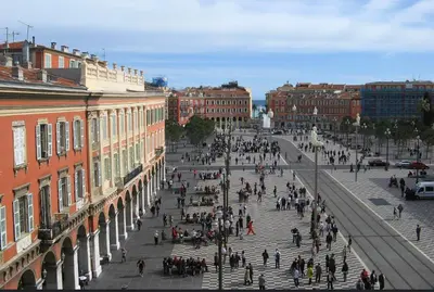 a group of people walking down a city street at Gustave in Nice