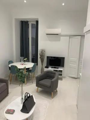 a living room with a table and a couch and a table and chairs at Gustave in Nice