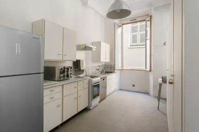 a kitchen with white cabinets and a refrigerator at Appartement Verrière - Welkeys in Nice