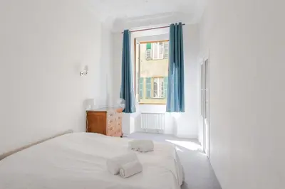 a white bedroom with a bed and a window at Appartement Verrière - Welkeys in Nice