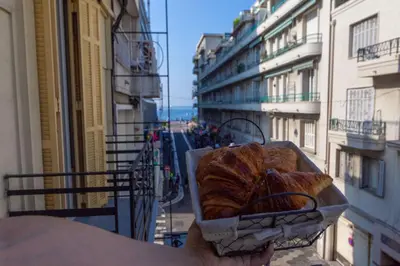 a person holding a basket of bread on a balcony at 100m from the sea in Nice