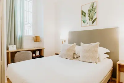 a bedroom with a large white bed and a desk at Palm Boutique Hôtel Nice in Nice