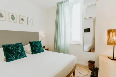 a bedroom with a large white bed with blue pillows at Palm Boutique Hôtel Nice in Nice