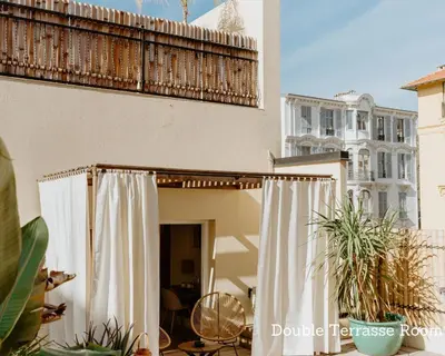a balcony of a house with white curtains and plants at Palm Boutique Hôtel Nice in Nice