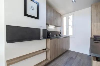 a kitchen with white walls and wooden cabinets at Cosy 1 Bdr near Garibaldi Square - Top Floor & AC in Nice