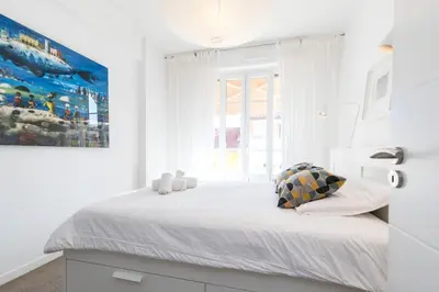a white bedroom with a large bed and a large window at Cosy 1 Bdr near Garibaldi Square - Top Floor & AC in Nice