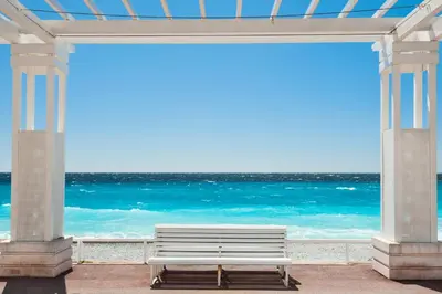 a white bench sitting in front of the ocean at Apartment Claudia - Central -Quiet- Near the Sea- AC- Private Parking in Nice