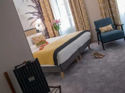 a hotel room with two beds and a chair at Mercure Nice Marché Aux Fleurs in Nice