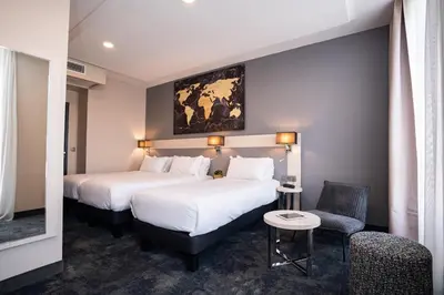a hotel room with two beds and a chair at Hôtel Univers in Nice