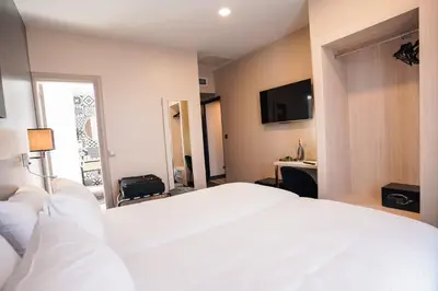a bedroom with a large white bed and a mirror at Hôtel Univers in Nice