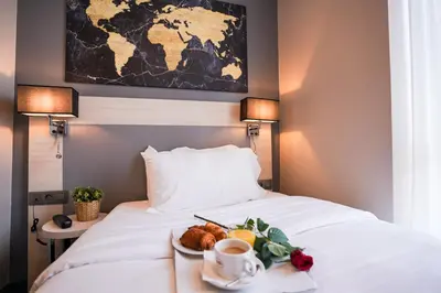 a tray of food on a bed with a plate of fruit at Hôtel Univers in Nice