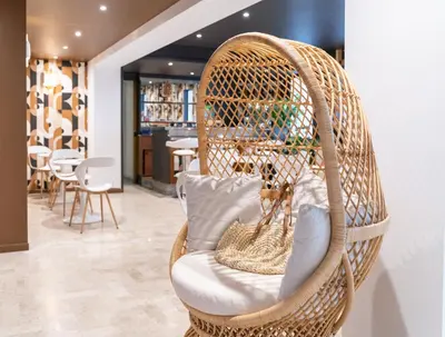 a wicker chair with a pillow in a room at Hôtel Comté de Nice in Beaulieu-sur-Mer