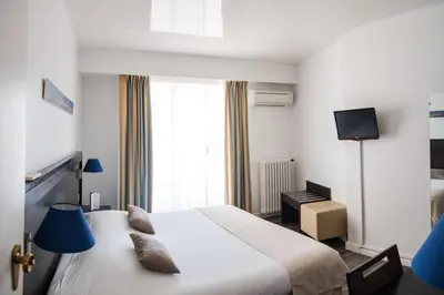 a hotel room with a bed and a tv at Hôtel Comté de Nice in Beaulieu-sur-Mer