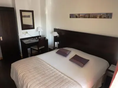 a bedroom with a bed and a desk with a desk at Hôtel Comté de Nice in Beaulieu-sur-Mer
