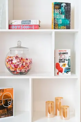 a shelf with a bowl of candy and books at Hôtel Comté de Nice in Beaulieu-sur-Mer