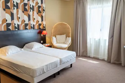 a hotel room with a bed and a chair at Hôtel Comté de Nice in Beaulieu-sur-Mer