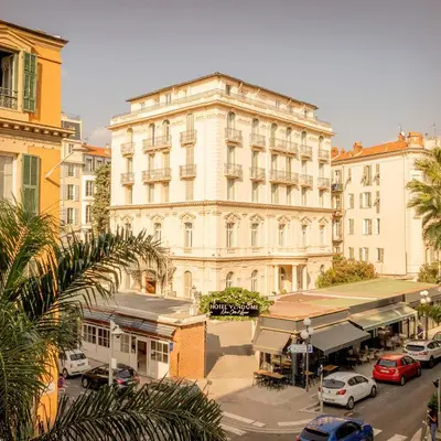 a large white building with cars parked in front of it at Hôtel Vendôme in Nice