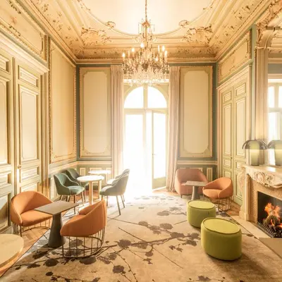 a room with chairs and tables and a chandelier at Hôtel Vendôme in Nice