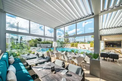 a restaurant with tables and chairs and a pool at Radisson Hotel Nice Airport in Nice