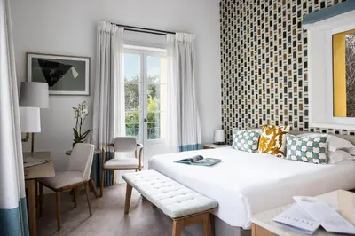 a bedroom with a white bed and a table and chairs at Hotel Royal-Riviera in Saint-Jean-Cap-Ferrat