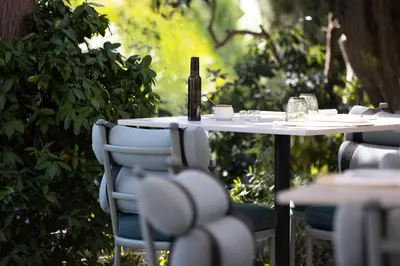 a white table with chairs and a bottle of wine on it at Hotel Royal-Riviera in Saint-Jean-Cap-Ferrat