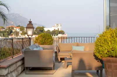 a balcony with couches and a view of the ocean at Hotel Royal-Riviera in Saint-Jean-Cap-Ferrat