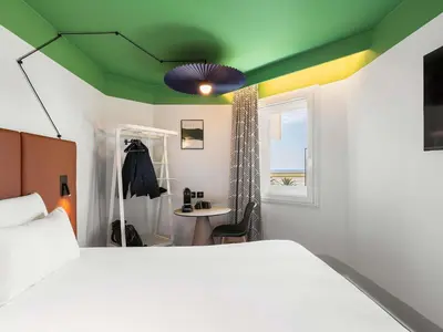 two beds in a hotel room with white sheets at ibis Nice Aéroport Promenade des Anglais in Nice