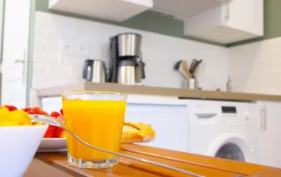 a glass of orange juice sitting on a table with a plate of food at LE REFUGE avec terrasse et jardin, en plein centre-ville, gare 5 minutes à pieds in Nice