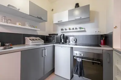 a small kitchen with white cabinets and a stove at Cosy Studio at Nice Port in Nice