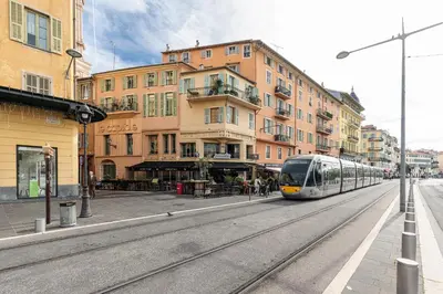 a train on the tracks in a city with buildings at Cosy Studio in the Old Town near Garibaldi Square in Nice