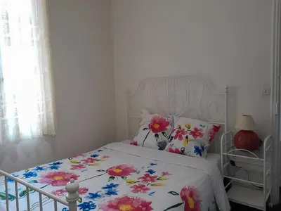 a bedroom with a white bed with a floral bedspread at Les Palmiers NiceAirport, Beach200m, 2bedrooms, Wifi Optic in Nice
