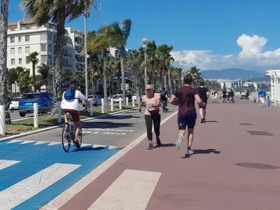 a group of people walking and riding bikes on a sidewalk at Les Palmiers NiceAirport, Beach200m, 2bedrooms, Wifi Optic in Nice