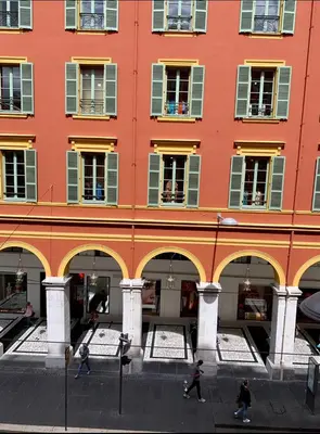 people walking in front of a large orange building at Jean in Nice