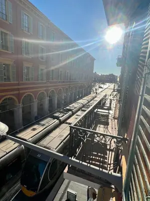 a train on a track in a city with a building at Jean in Nice