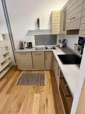 a kitchen with white cabinets and a wooden floor at Jean in Nice
