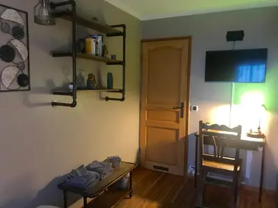 a room with a table and a chair and a television at Chambres chez l'habitant Villa l'Île aux Anges in Saint-Andre-de-la-Roche